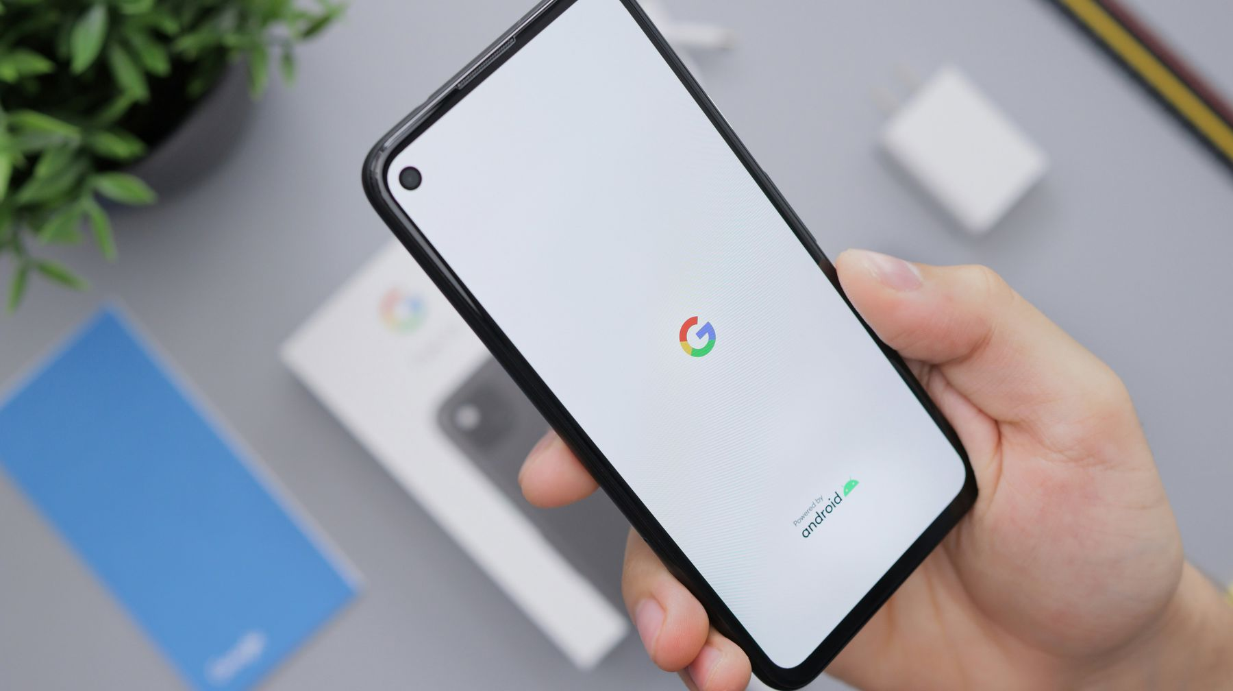 Hand holding a smartphone with the Google app loading