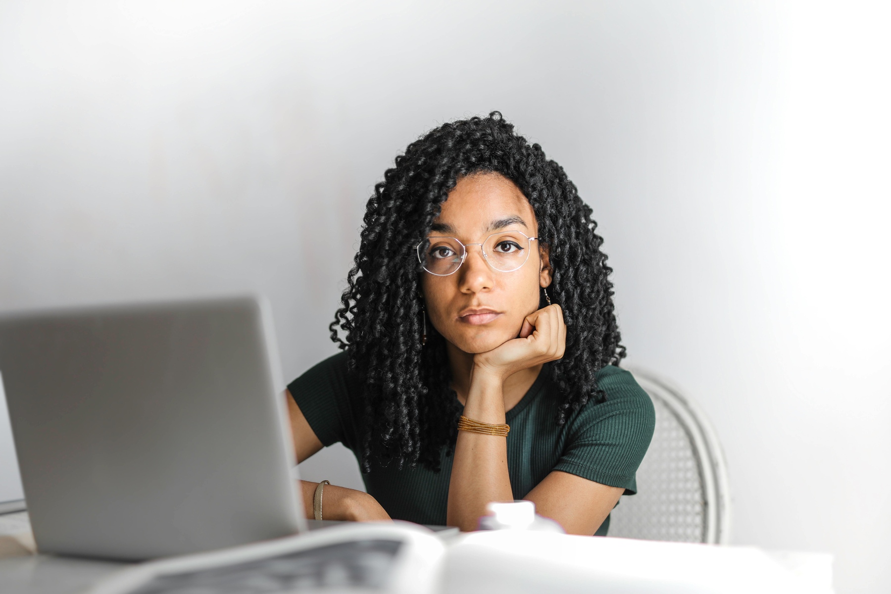 Woman with her hand on her chin, with her laptop in front of her