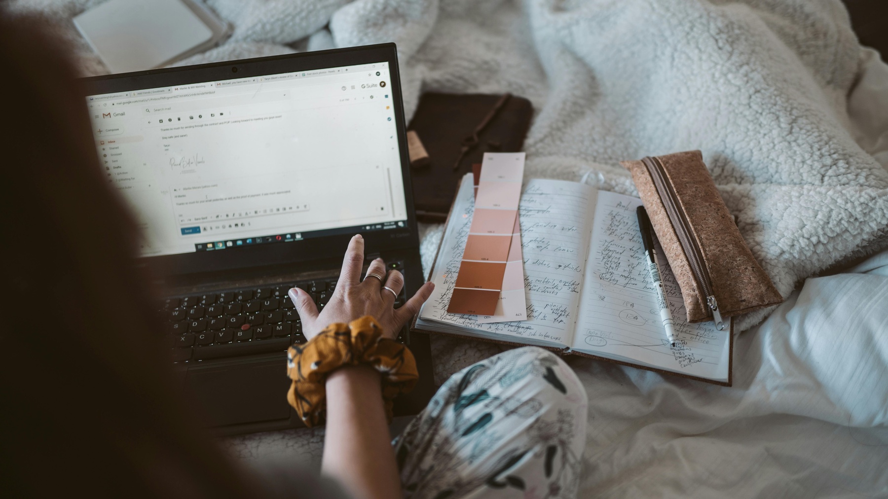 Woman writing an email with color swatches and her notebook open