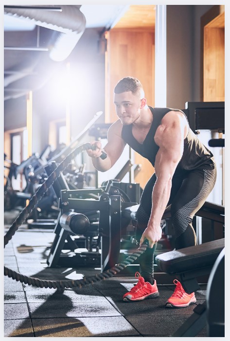A man using battle ropes at the gym for a high-intensity workout.