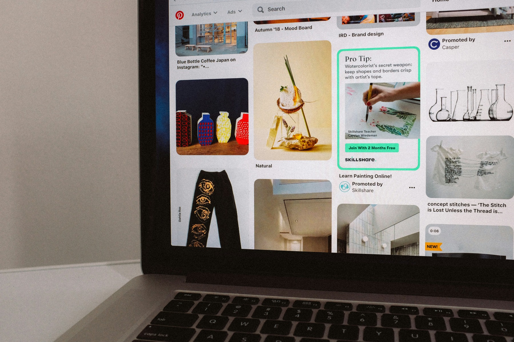 A laptop displaying a Pinterest feed with various creative and promotional posts